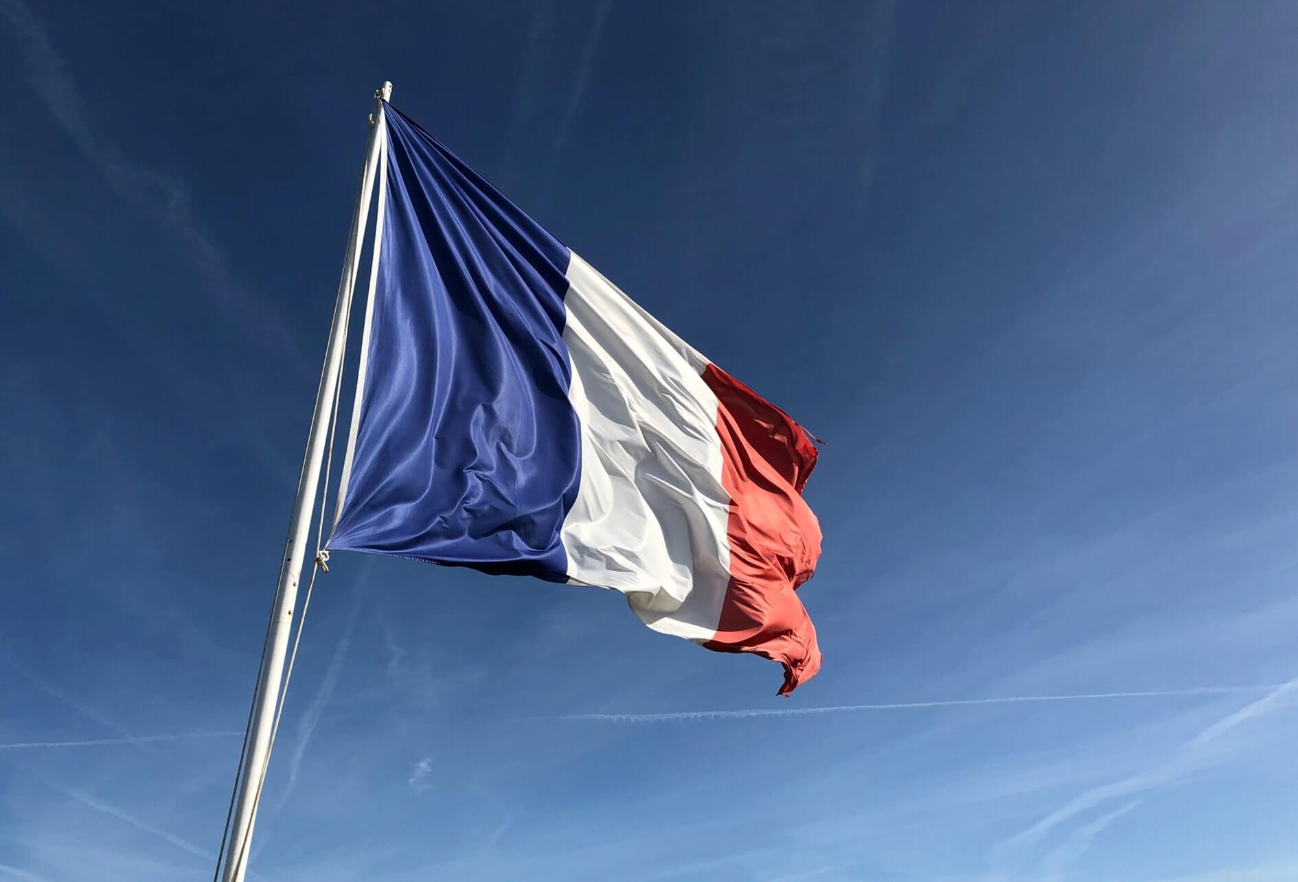 Appui soutien gestion des Autorités publiques Couleur du drapeau français flottant au vent au sommet d'un mât, au fond le ciel en camaïeu de bleu.