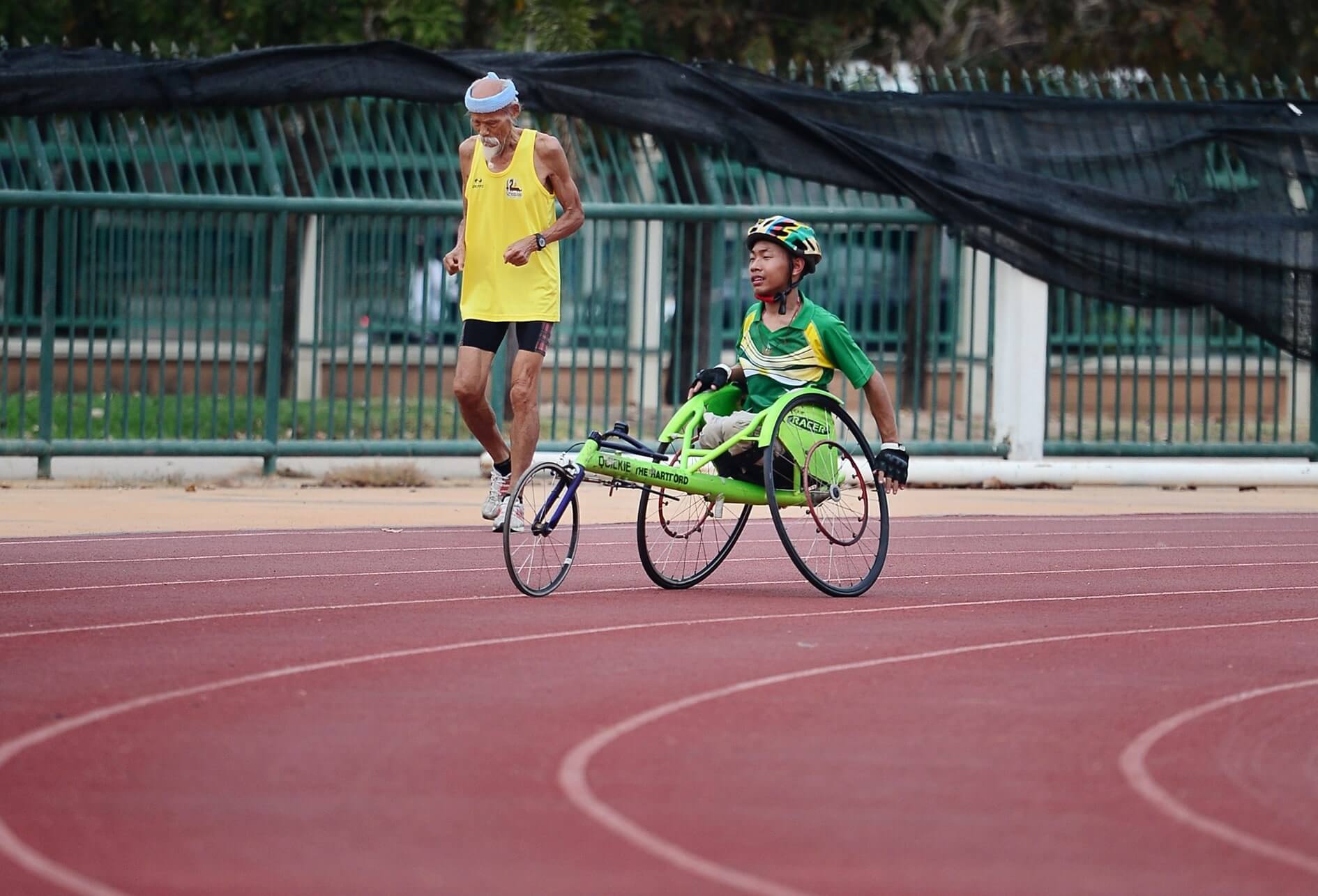 Accessibilité pour tous, égalité des chances Sur une piste d’athlétisme, 2 coureurs, l’un d’un âge vénérable, l’autre en fauteuil roulant sport