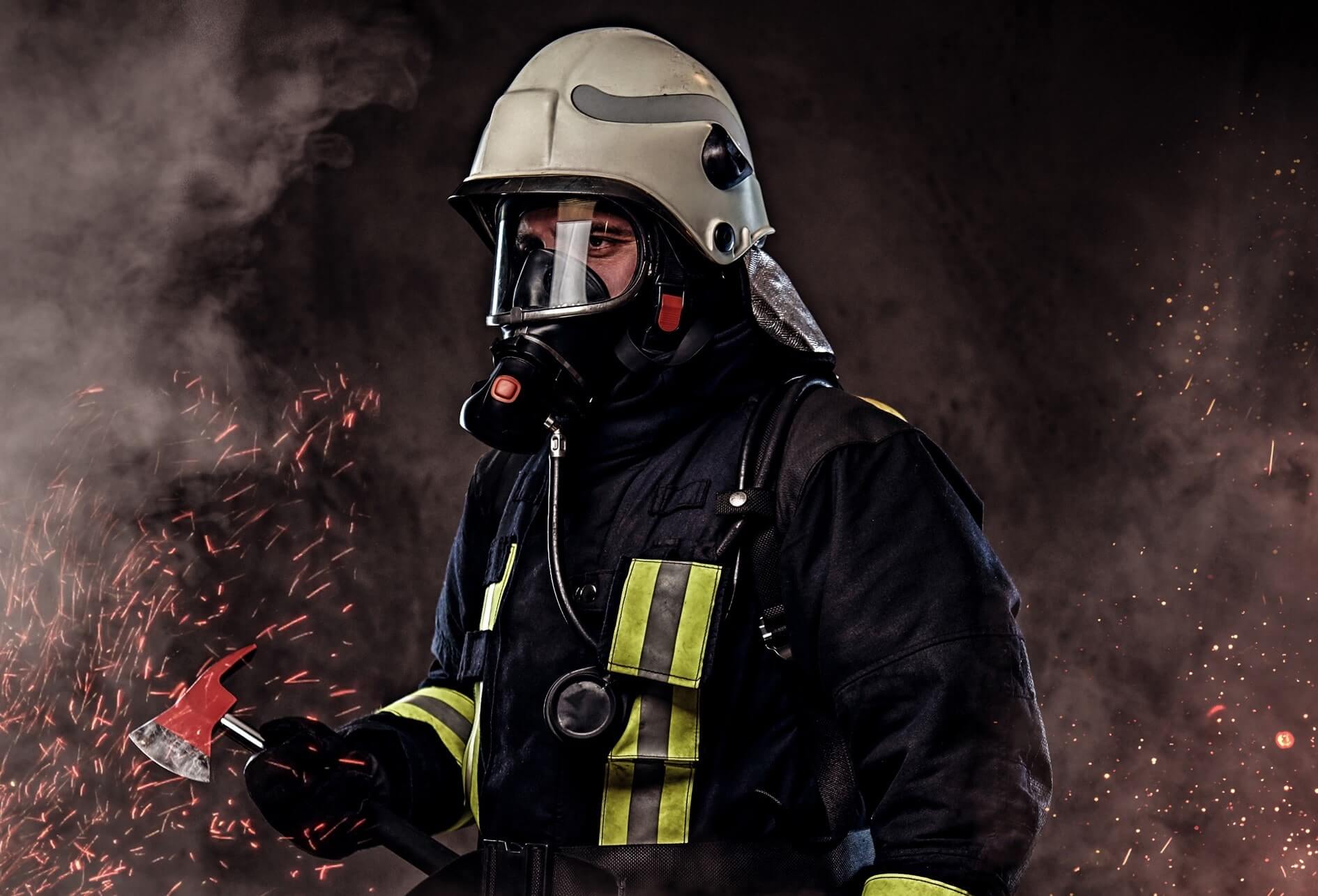Sécurité de lutte incendie Dans une ambiance sombre, de fumée, de brandons, un pompier équipé lourdement