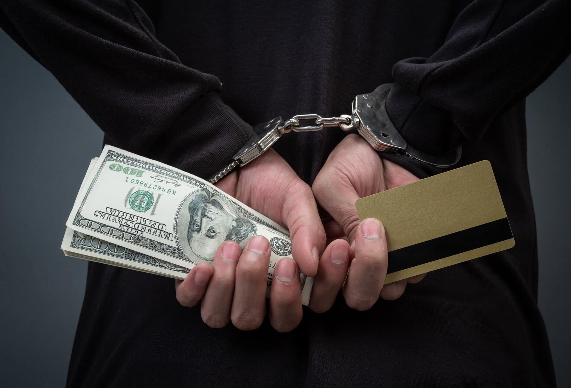 Sécurité économique Humain menotté dans le dos tenant des billets de banque et une carte de crédit