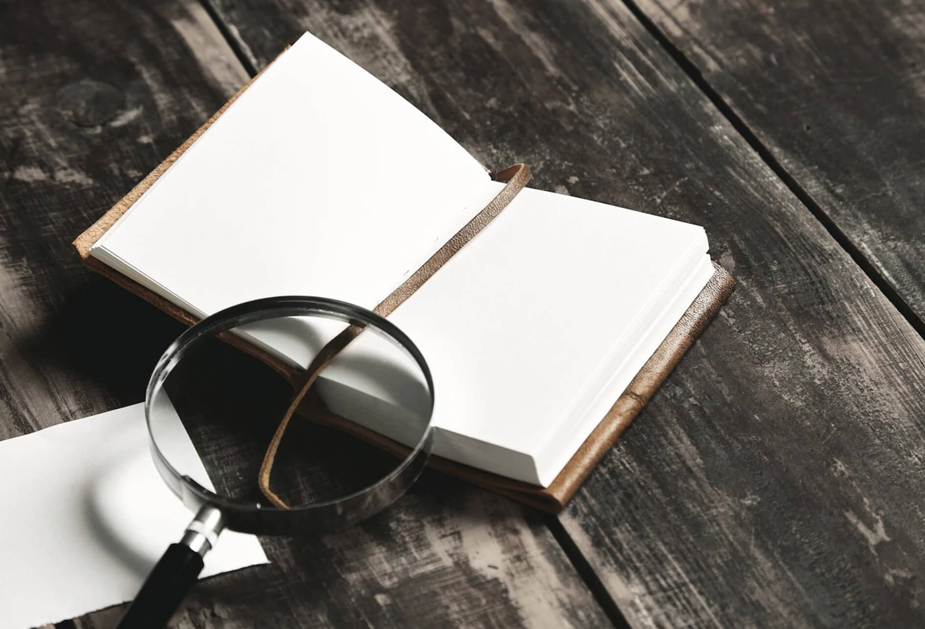 Audit diagnostic QHSE Sur une table, une loupe sur un carnet grand ouvert et une feuille volante