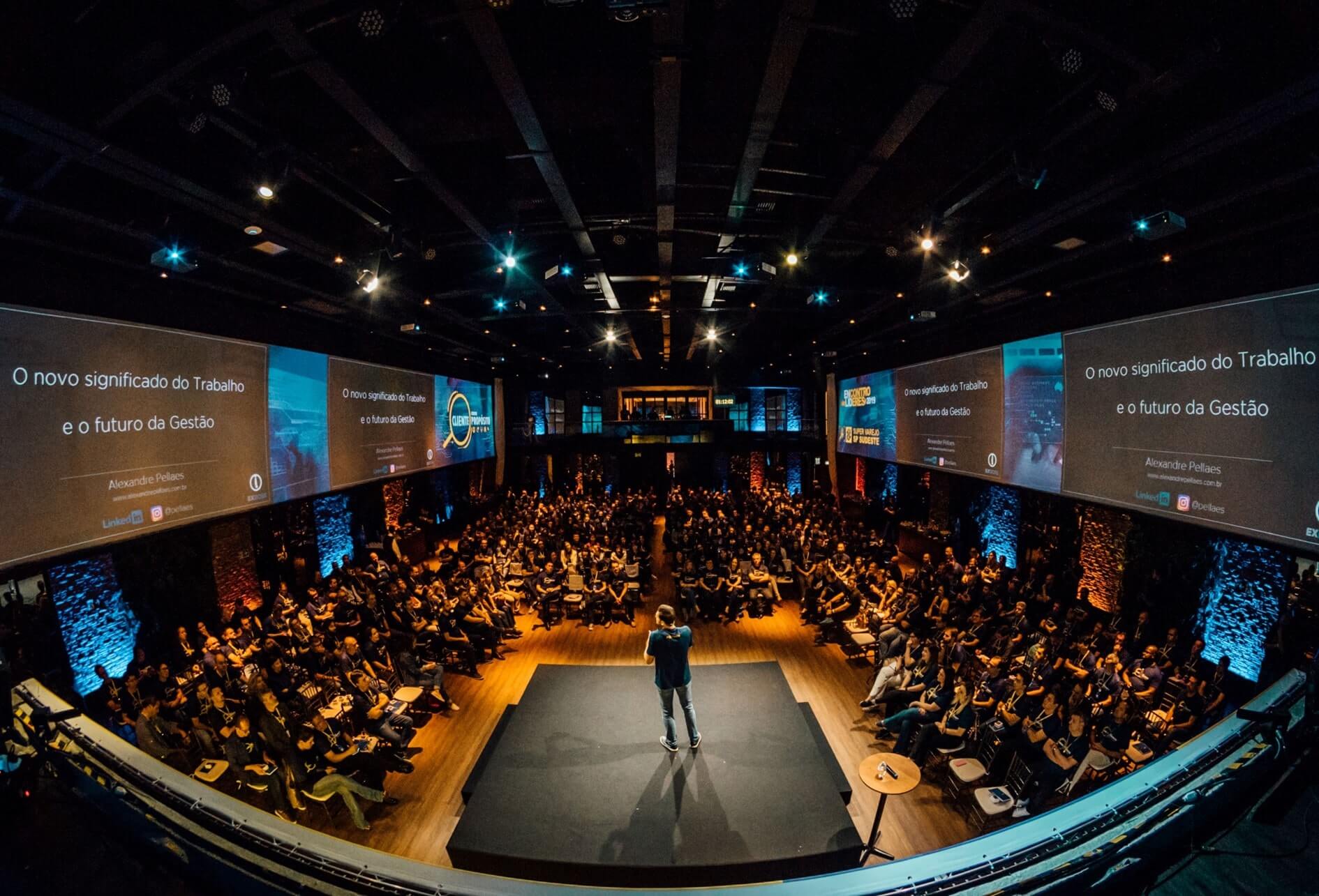 Vue panoramique d’une salle de conférence avec, au premier plan, le conférencier sur une estrade.