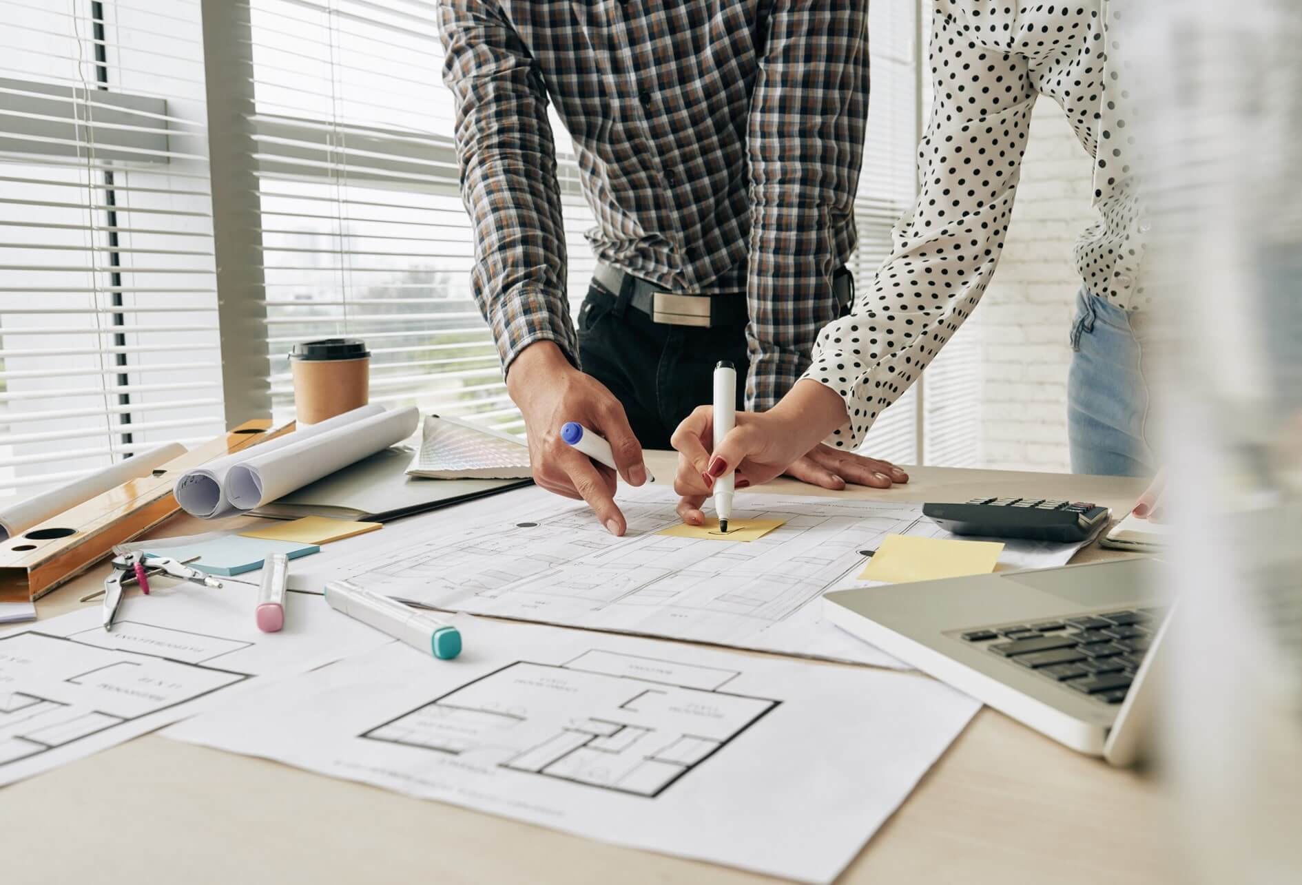 Deux Humains réalisant une étude technique de plan d’architecture sur une table