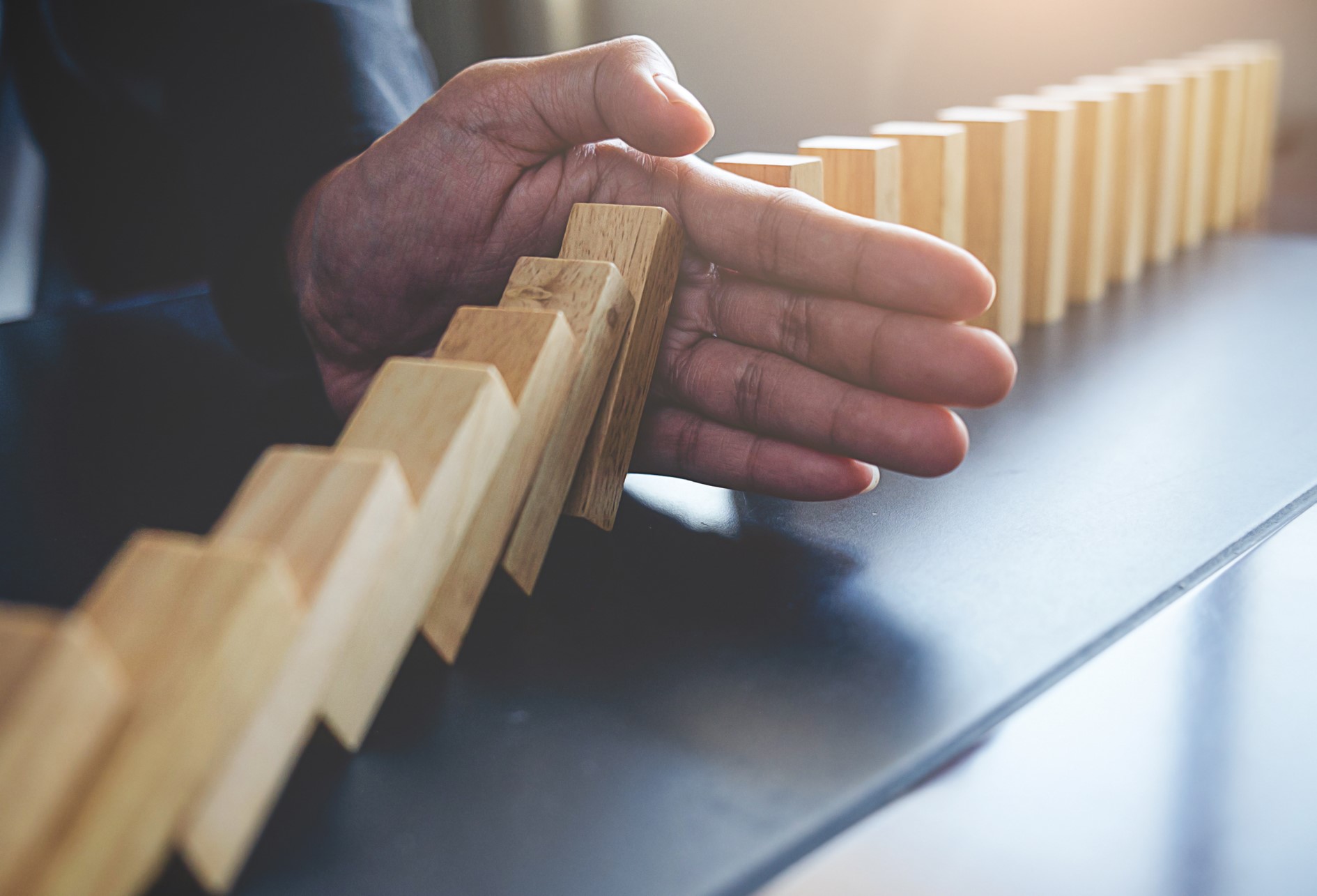 Jeu de domino en équilibre sur une table qu’une main arrête